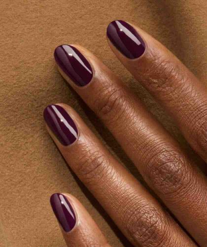 Main féminine, vernis Aubergine GREEN™ Manucurist, bordeaux-violet foncé, manucure glamour et raffinée L'Officina Paris