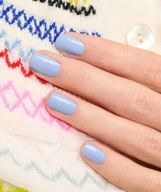 Lilas GREEN™ Manucurist, manucure bleu pastel sur mains en lumière naturelle, élégance douce