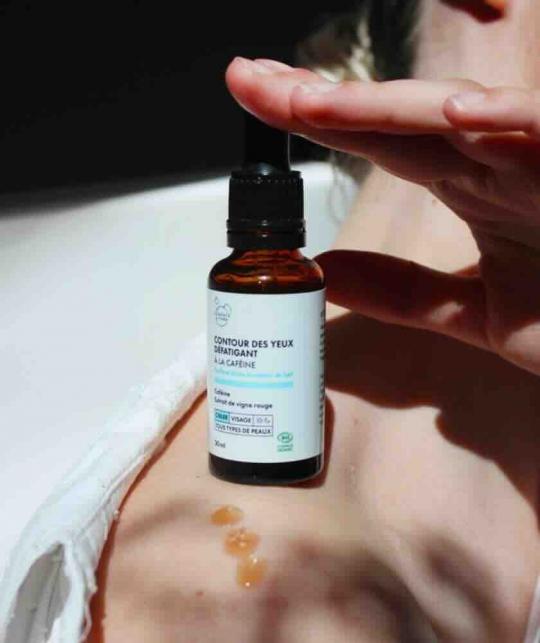 Contour des Yeux Défatigant Clémence & Vivien, flacon éclairé sur une peau féminine lumineuse