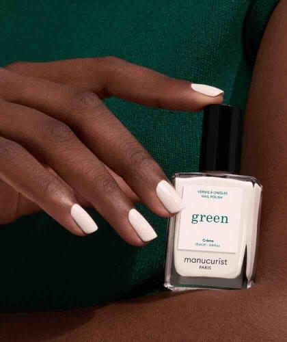 Crème GREEN™ Manucurist nail polish held in a hand with medium-dark skin
