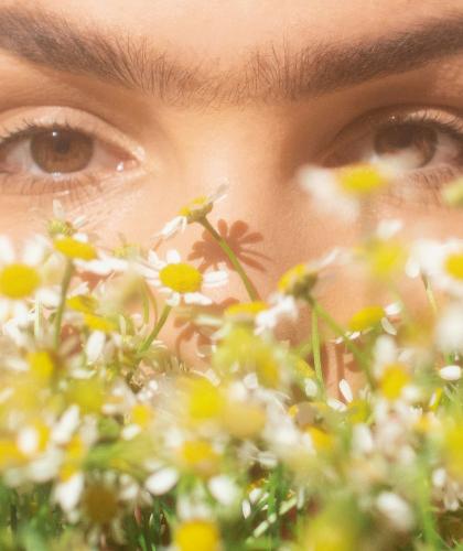 Woman with a radiant complexion surrounded by plants – Joveda Ayurvedic skincare made in India