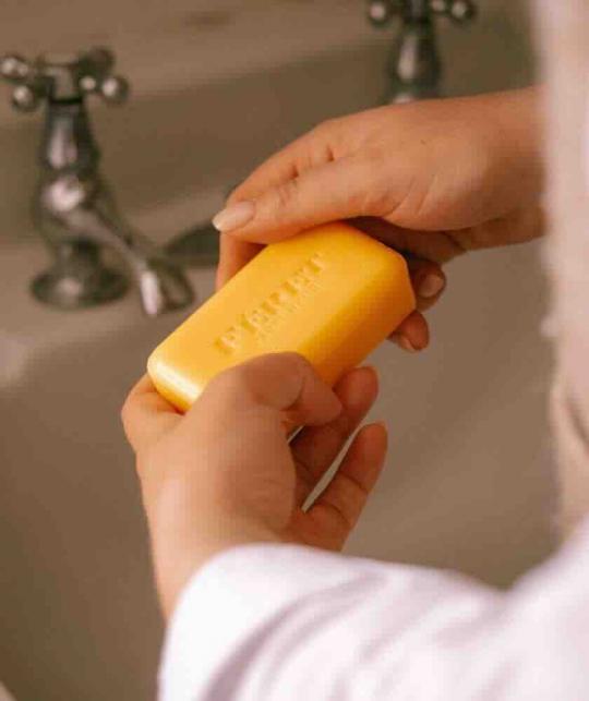 Savon Parfum Miel Féret Parfumeur dans les mains d’une femme au-dessus d’un lavabo rétro